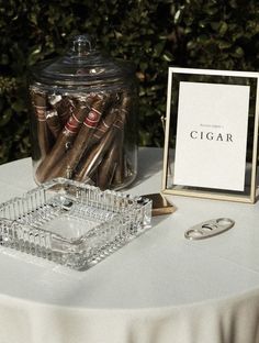 there is a glass jar with cigars in it and a sign on the table