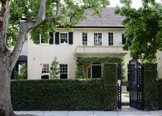 a white house with ivy on the front and side walls, surrounded by large trees