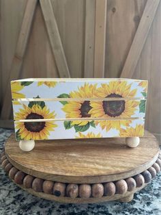 a wooden box with sunflowers painted on the front and sides, sitting on top of a table