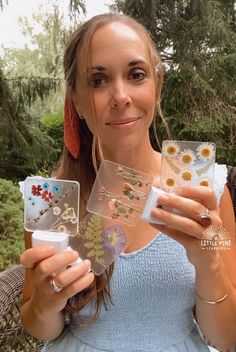 a woman is holding up some cards with flowers on them