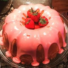 a cake with pink icing and strawberries on top is sitting on a plate