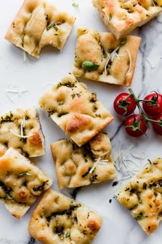 small crackers with cheese, herbs and tomatoes on a marble surface next to some red peppers