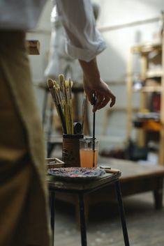 a person is painting on an easel with paintbrushes and brushes in it