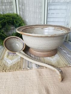 a bowl and spoon sitting on top of a table next to a window sill