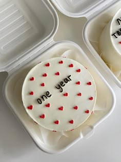 two plastic containers filled with white cake covered in frosting and red hearts that say one year