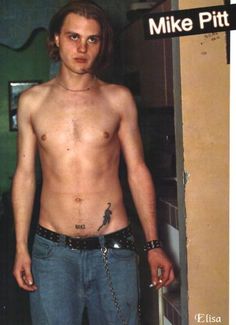 a man without a shirt is holding a chain and looking at the camera while standing in front of a door