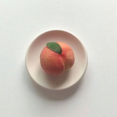 an apple with a leaf in a white bowl