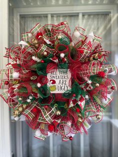 a red and green christmas wreath hanging from the front door with words written on it