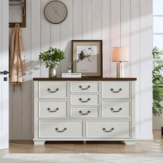 a white dresser sitting in a living room next to a clock