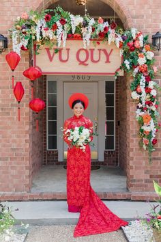 a woman standing in front of a building with flowers and decorations on the outside wall