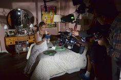 a woman sitting on top of a bed next to a camera