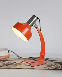 an orange desk lamp sitting on top of a book