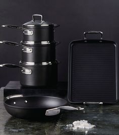 an assortment of cooking utensils and pans on a counter with black background