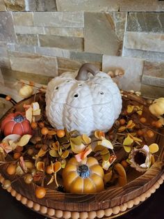 decorative pumpkins and gourds are arranged in a basket on a table top