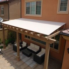 an outdoor living area with couches, table and grill in front of a house