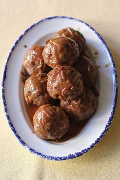 meatballs covered in gravy on a white and blue plate