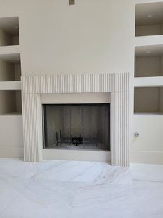 an empty room with white walls and a fireplace