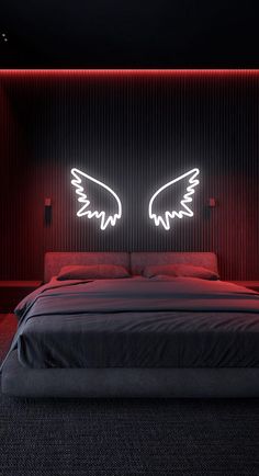 a bed with two wings on the headboard in a dark room next to a red wall