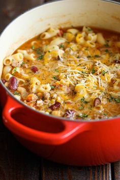 a red pot filled with pasta and meat soup