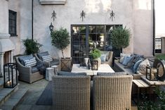 an outdoor living area with wicker furniture and potted plants on the side of the building