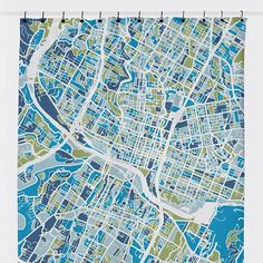 a blue and green city map shower curtain hanging on a white bathroom wall next to a toilet