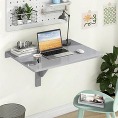 a laptop computer sitting on top of a desk next to a potted green plant