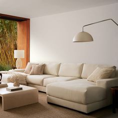 a living room with white couches and pillows on the floor next to a large window