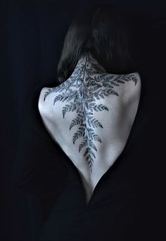 the back of a woman's neck with leaves painted on it