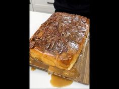 a cake sitting on top of a wooden cutting board covered in icing and pecans