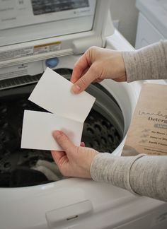 two hands holding business cards next to a washing machine