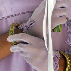 a close up of a person wearing white gloves and bracelets with flowers on them