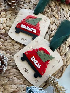 two personalized christmas ornament hanging from a basket with pine cones and decorations