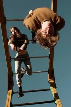 two people are hanging upside down on a ladder