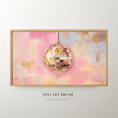 a mirror ball hanging on the wall in front of a pink and yellow painting with words that read nin art brush