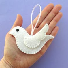 a hand holding a white ornament with a bird on it's back