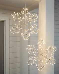 a lighted snowflake hanging from the side of a wall next to a door