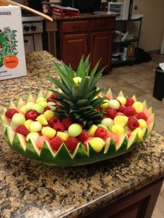 a pineapple and raspberry fruit arrangement on a kitchen counter