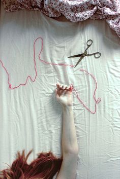 a woman laying on top of a bed next to a pair of scissors