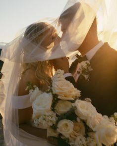 a bride and groom kissing under the veil