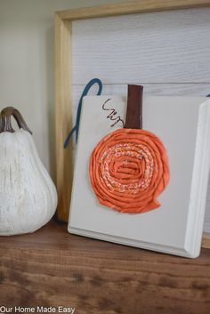 an orange piece of fabric sitting on top of a book next to a white pumpkin