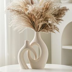 a white vase with some dried plants in it