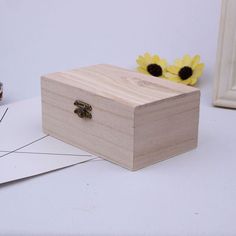 a wooden box sitting on top of a table next to a yellow flower and cupcake