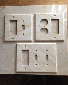 three white marble outlet covers sitting on top of a table