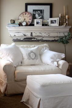 a living room with a white couch and ottoman next to a clock on the wall