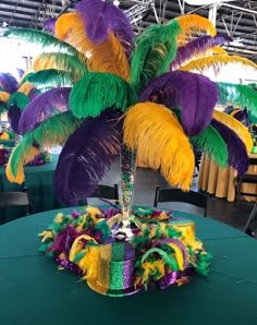 a table topped with a vase filled with purple, yellow and green feathered decorations