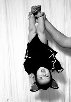 a black and white photo of a person holding a baby in the air with their hands