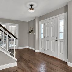 an empty living room with hardwood floors and white trim on the doors, windows, and stairs