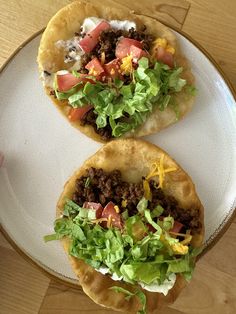 two pita breads with lettuce, tomatoes and other toppings on a plate