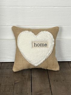 a pillow with the word home written on it and a heart shaped pillow in front