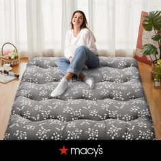 a woman sitting on top of a mattress in the middle of a room with curtains